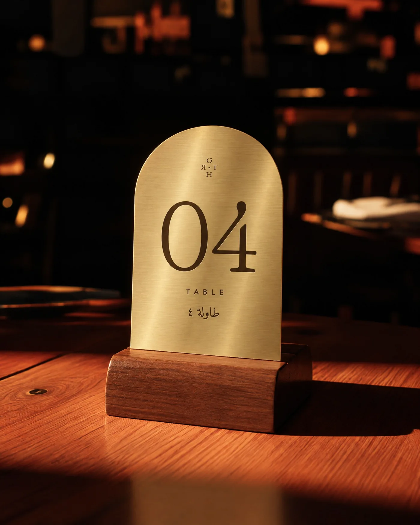 Arched brass table number in a walnut block